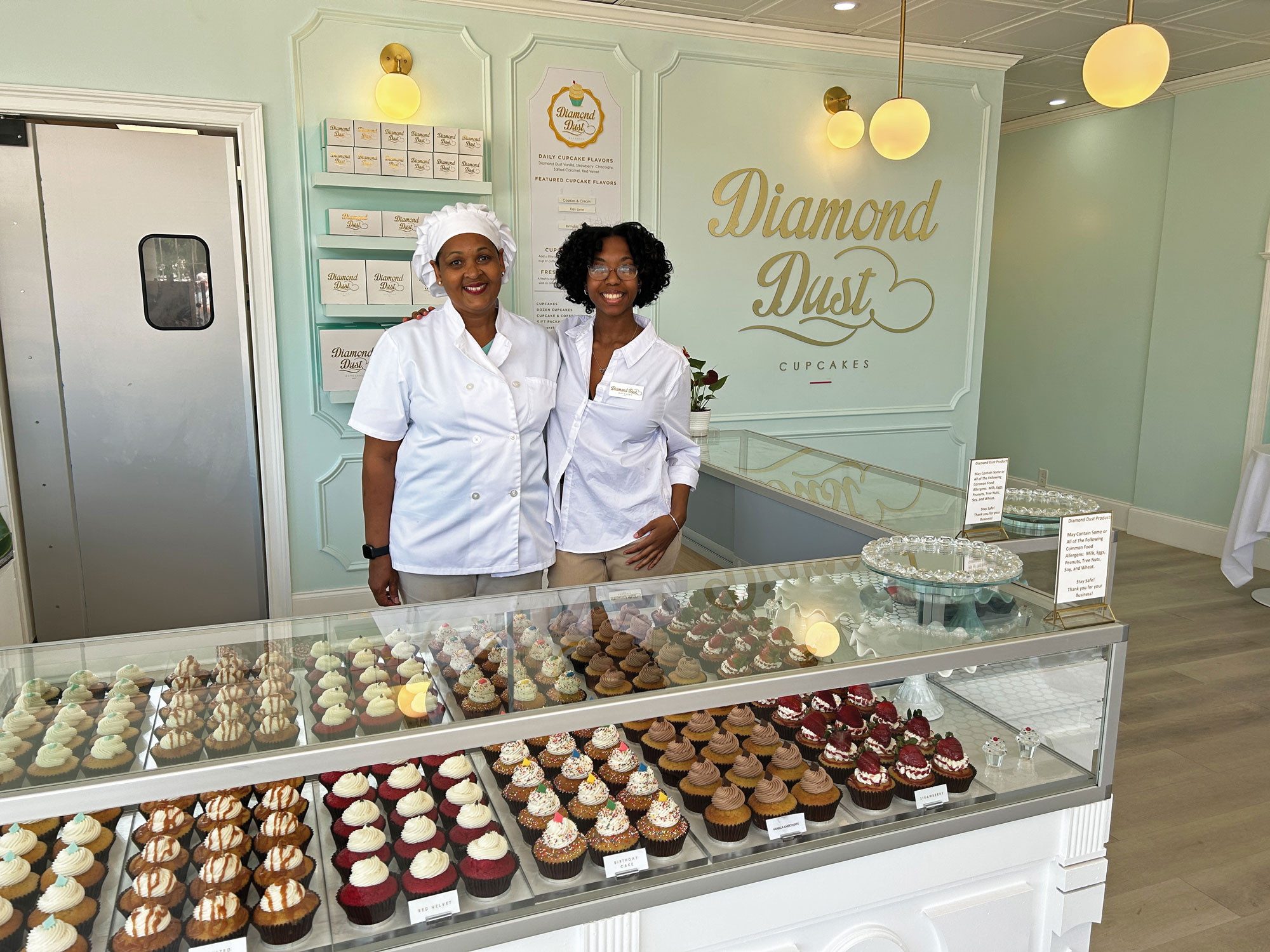 Two women stand behind cupcake counter at Diamond Dust