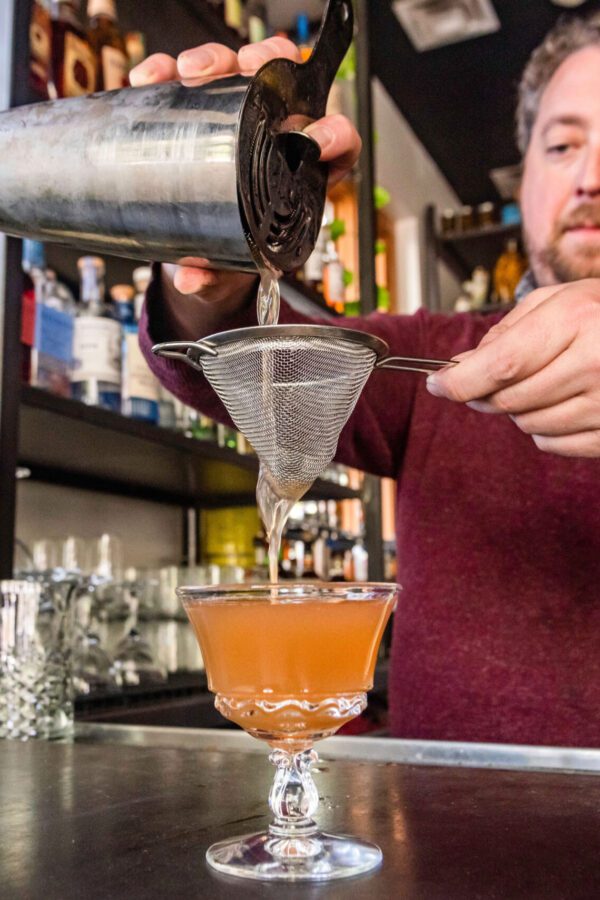 bartender strains drink at The Deer and The Dove