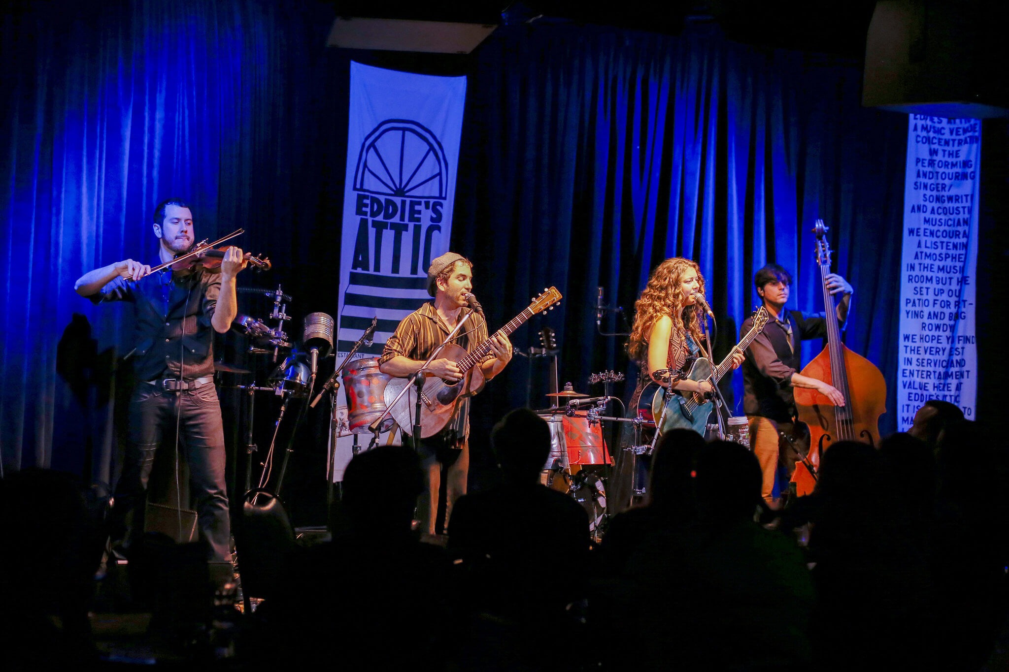 band on small stage with curtained background and "Eddie's Attic" banner