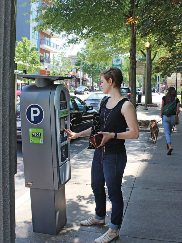 woman pays for parking at pay station