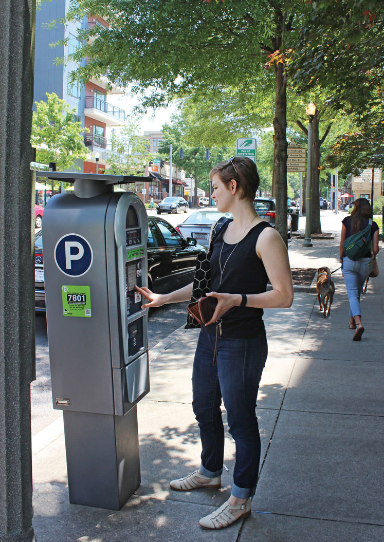 woman pays for parking at pay station