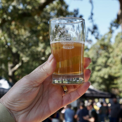 hand holding beer tasting glass outside