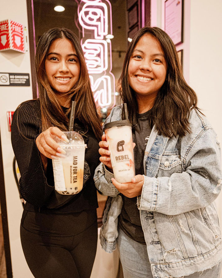 two girls hold up their Rebel Teahouse bubble tea drinks