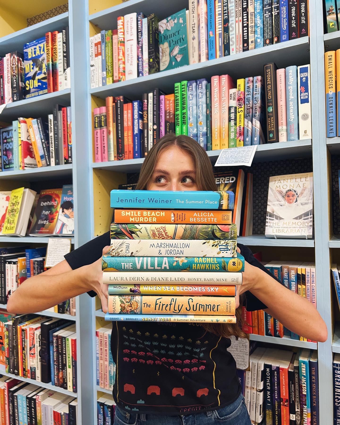 Woman holds stack of books at Little Shop of Stories