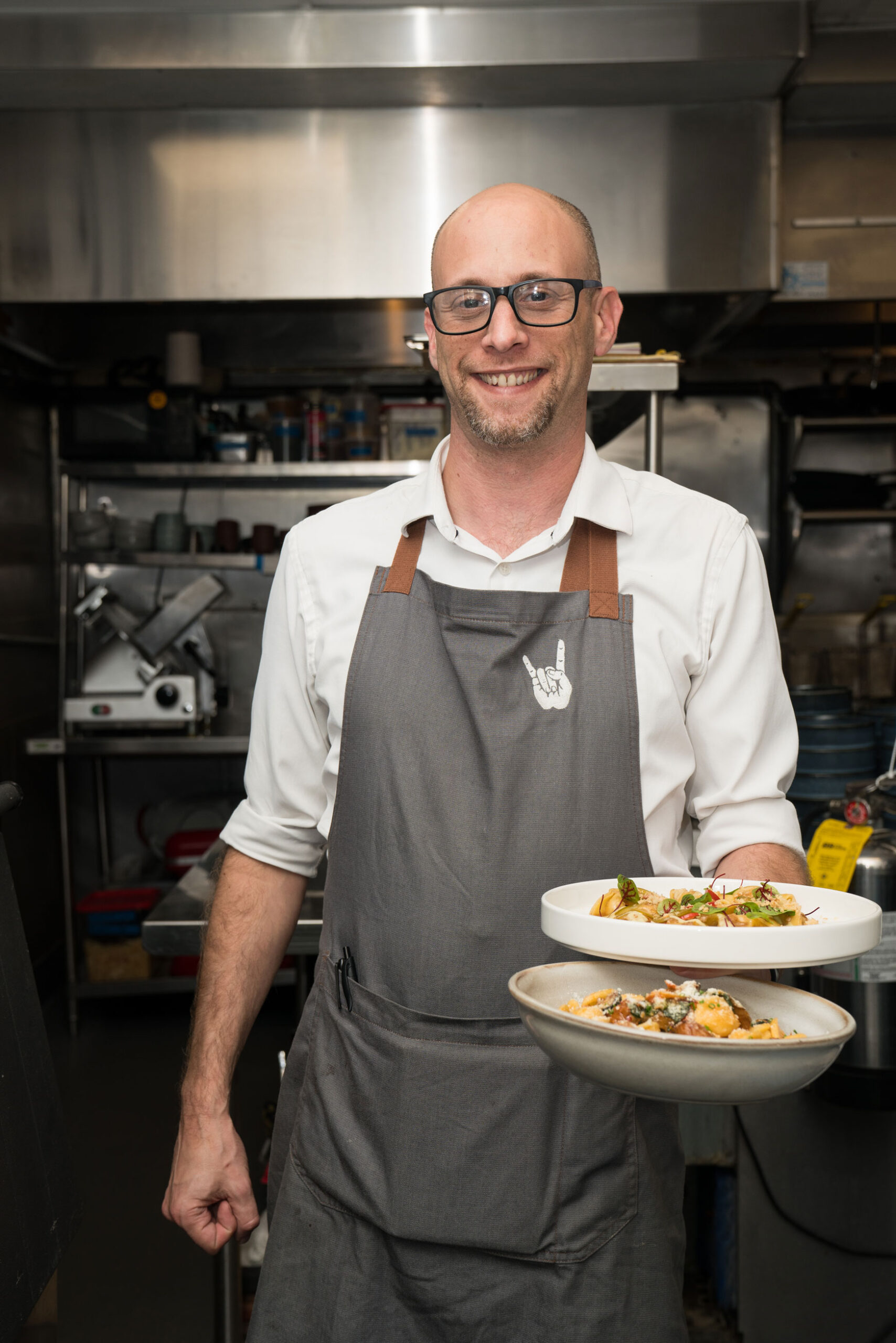 Smiling waiter holding multiple pasta dishes